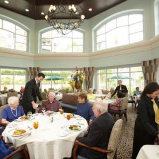 A group of people dining in a well-lit restaurant setting, with waitstaff attending to them.