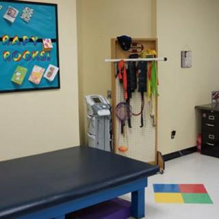 A physical therapy room equipped with a variety of exercise tools and a treatment table.