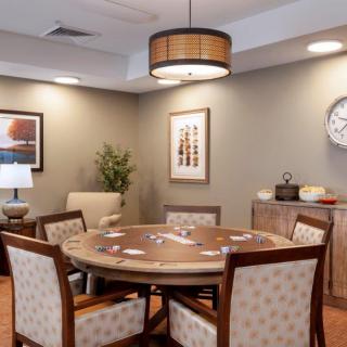 A cozy dining room with a round table and upholstered chairs, featuring elegant decor and artwork.