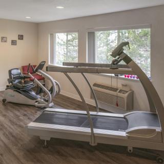 A small gym room featuring a treadmill and other exercise equipment.