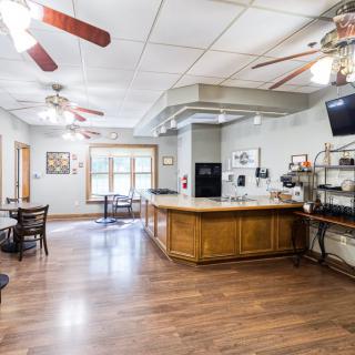 A spacious kitchen and bar area with wooden flooring and ceiling fans.