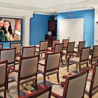 An empty meeting room with rows of chairs facing a projector screen.