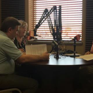 A group of people engaging in a radio interview or podcast discussion in a studio setting.