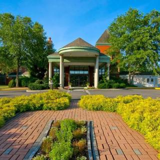 A beautiful entrance to a building with lush landscaping and a brick pathway.