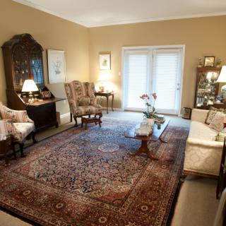 A traditionally decorated living room featuring antique furniture and a large patterned carpet.