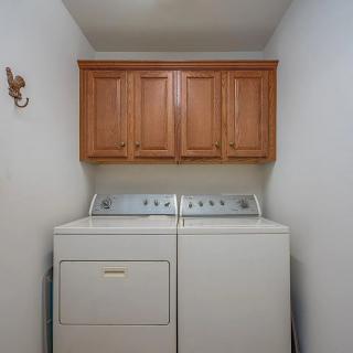 A compact laundry room with a washing machine and dryer beneath wooden cabinets.