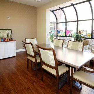 A cozy dining room with a wooden table, comfortable chairs, and a large window letting in natural light.