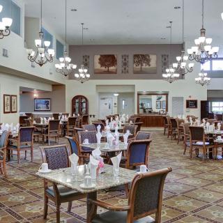 A spacious dining area with elegant chandeliers and neatly arranged tables.