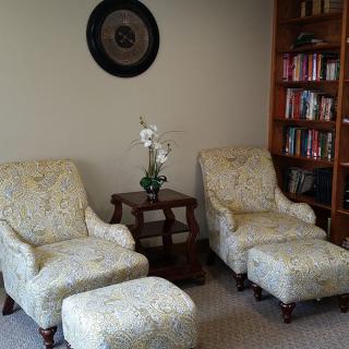 Cozy living room with patterned armchairs and a well-stocked bookshelf.