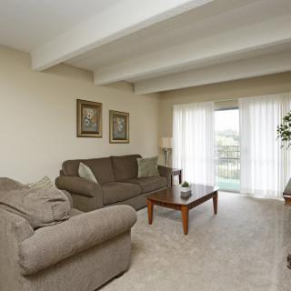 A cozy living room with comfortable sofas, a coffee table, and large windows covered by curtains.