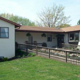 A single-story house with a fenced yard and lush green lawn.
