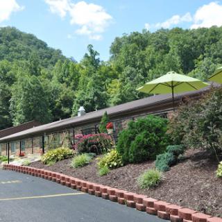 A scenic view of a building surrounded by lush greenery and colorful flowers, featuring an outdoor umbrella for shade.