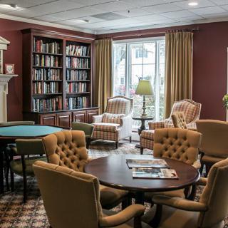 A cozy library room with bookshelves, armchairs, and tables for reading and relaxation.
