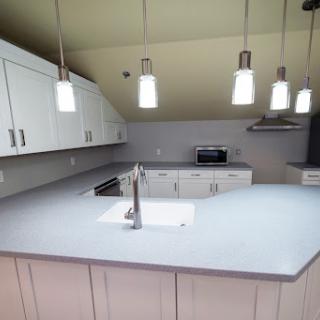 A modern kitchen featuring white cabinets, a sleek countertop, and stylish pendant lighting.