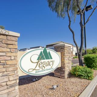 Entrance sign for Legacy property with landscaping and brick wall.