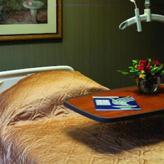 A well-arranged hospital room featuring a bed with a charming floral arrangement on the tray.