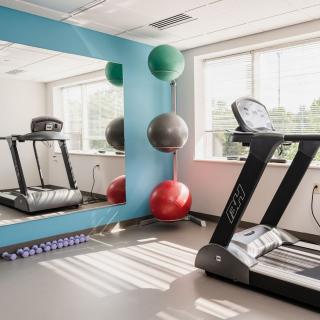 A bright and well-equipped gym with a treadmill, yoga mat, and exercise balls.