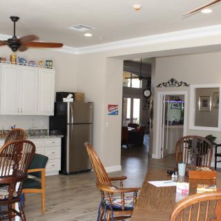 A spacious kitchen and dining area featuring a ceiling fan, wooden furniture, and modern appliances.