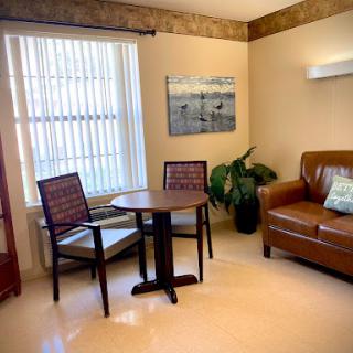 A cozy living room setup featuring a comfortable sofa, a small table with chairs, and decorative artwork on the wall.