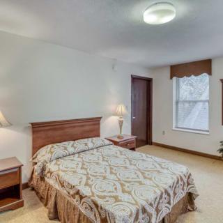 A cozy bedroom with a neatly made bed, nightstands, and a window providing natural light.