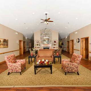 A cozy and elegantly designed living area featuring stylish armchairs, a sofa, and a central coffee table, accentuated by warm lighting and modern decor.