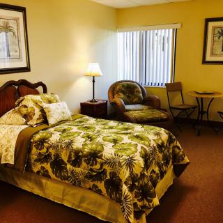 A cozy bedroom with a single bed, an armchair, and a small table near a window.