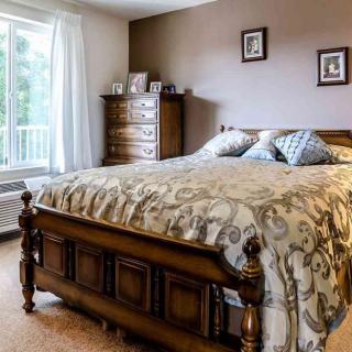 A cozy bedroom with a wooden bed and chest of drawers.
