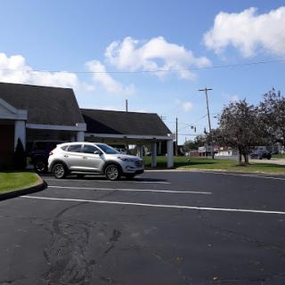 A white car parked in front of a building under a partly cloudy sky.