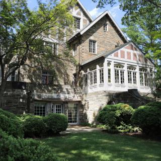 A beautiful stone house surrounded by lush greenery and a well-maintained garden.