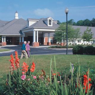 A scenic view of a landscaped garden in front of a building with people walking.
