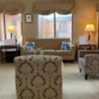 A cozy living room with comfortable seating, lamps, and large windows.
