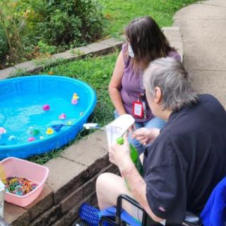 Two people engaging in outdoor activities next to a small pool filled with toys.