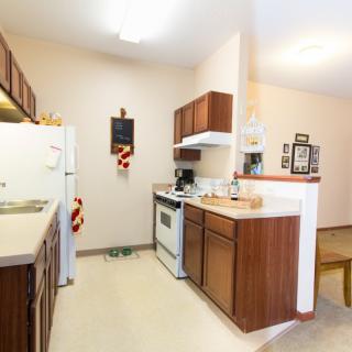 A cozy kitchen with wooden cabinets, a stove, and a refrigerator.