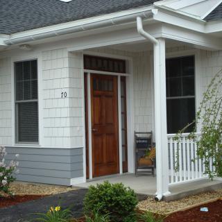 A cozy front porch of a house with a wooden door and small garden.
