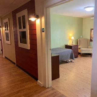 A cozy hallway leading to a warmly lit bedroom with wood flooring.
