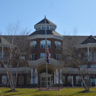 A symmetrical government building with flags in front, captured on a clear day.
