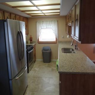 A modern kitchen with wooden cabinets, stainless steel appliances, and a window providing natural light.