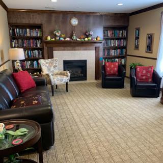 A cozy living room featuring comfortable seating, a fireplace, and an extensive bookshelf.