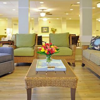 A cozy living room with comfortable seating, featuring a wicker coffee table adorned with a flower arrangement.