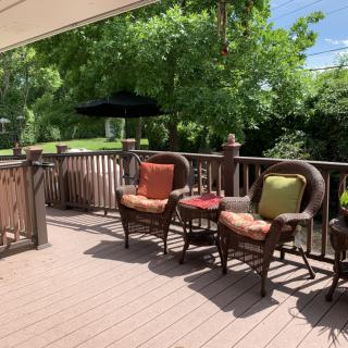 A sunny outdoor patio deck with comfortable seating and lush greenery.