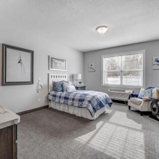 A cozy bedroom with a single bed, featuring blue bedding and ample natural light from a large window.