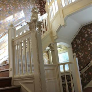 A beautifully designed interior staircase featuring elegant woodwork and floral wallpaper.