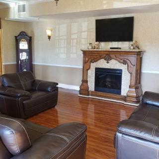 A traditional living room featuring leather chairs, a wooden fireplace, and a mounted television.