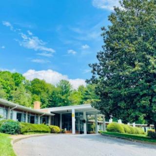 A serene view of a building surrounded by lush greenery and a clear blue sky.