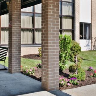Exterior view of a building with a garden, featuring flowers and a bench.