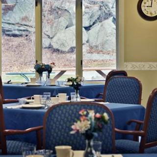 An elegantly set dining room with tables and chairs, featuring a view of the outside through large windows.