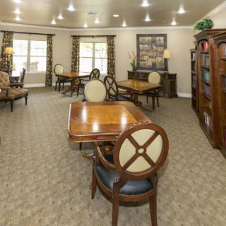 A cozy library room with wooden tables, comfortable chairs, and bookshelves filled with books.