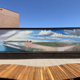 A vibrant mural depicting a serene coastal landscape under a blue sky with clouds.
