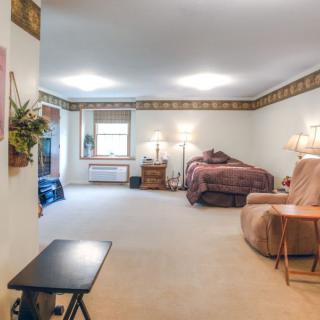 A cozy living space with a blend of living room and bedroom elements, featuring comfortable furniture, lamps, and decorative accents.