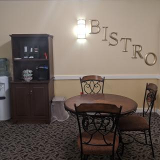 A cozy bistro corner with a table, chairs, and a cabinet with a water dispenser.